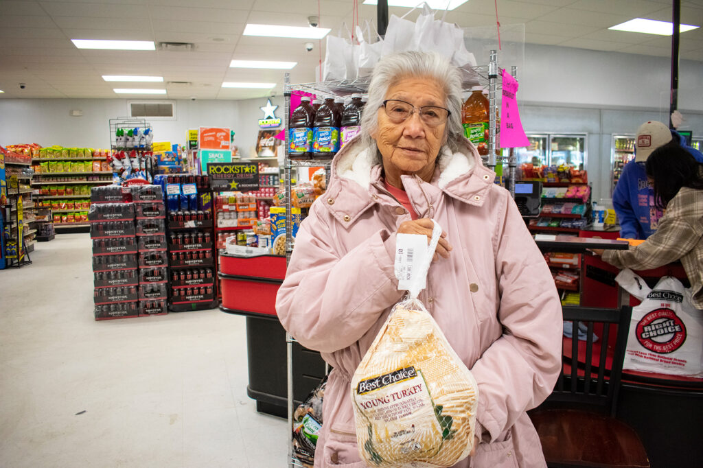 A person in a store holds a packaged turkey.