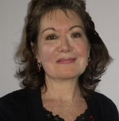 A woman with a black cardigan or blazer on and shoulder length hair smiling.