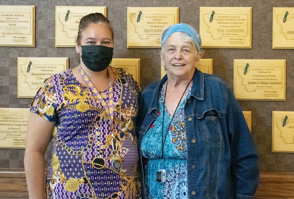 Two people are standing in front of dedication plaques.
