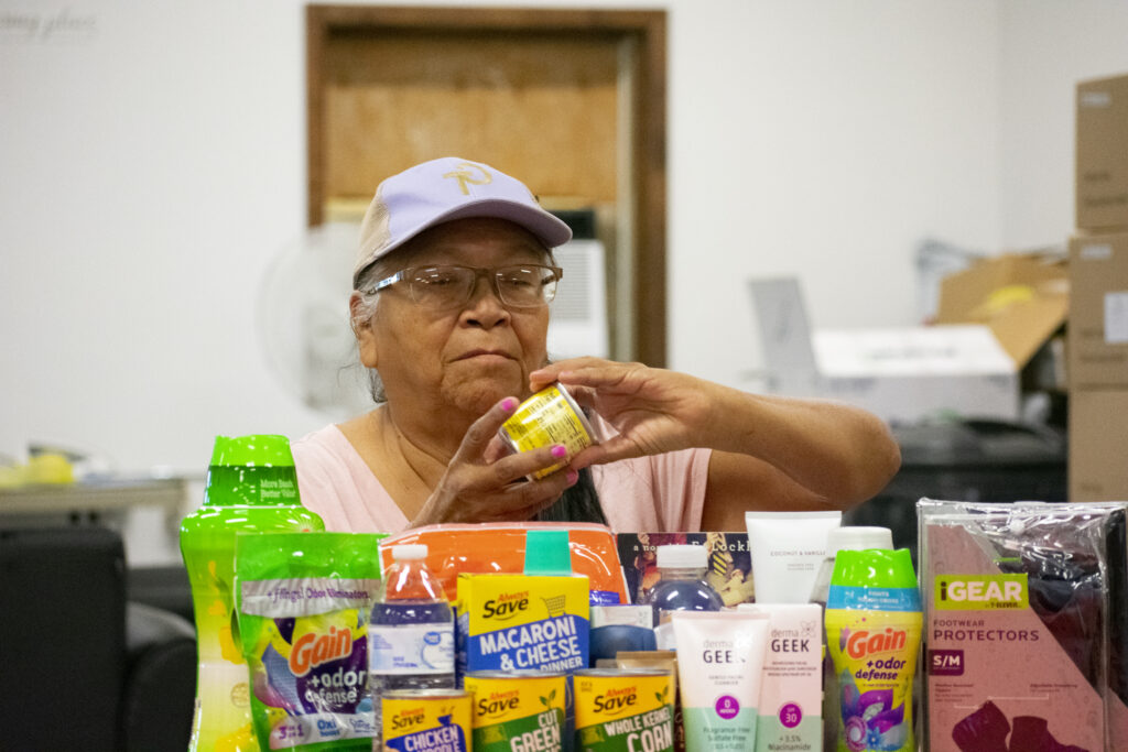 A person is handling a can among various household and personal care products.