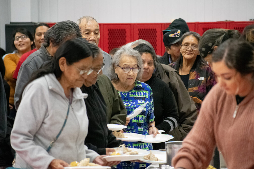 People gathered in a line, holding plates.